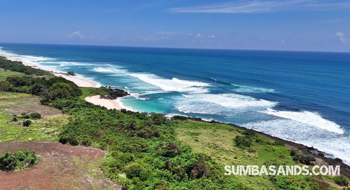 A panoramic aerial view of the Waibuku Private Beach Estate. The image captures 3.4 hectares of lush green land meeting a deep white-sand beach with turquoise waters in Pannengo Ede, Southwest Sumba.