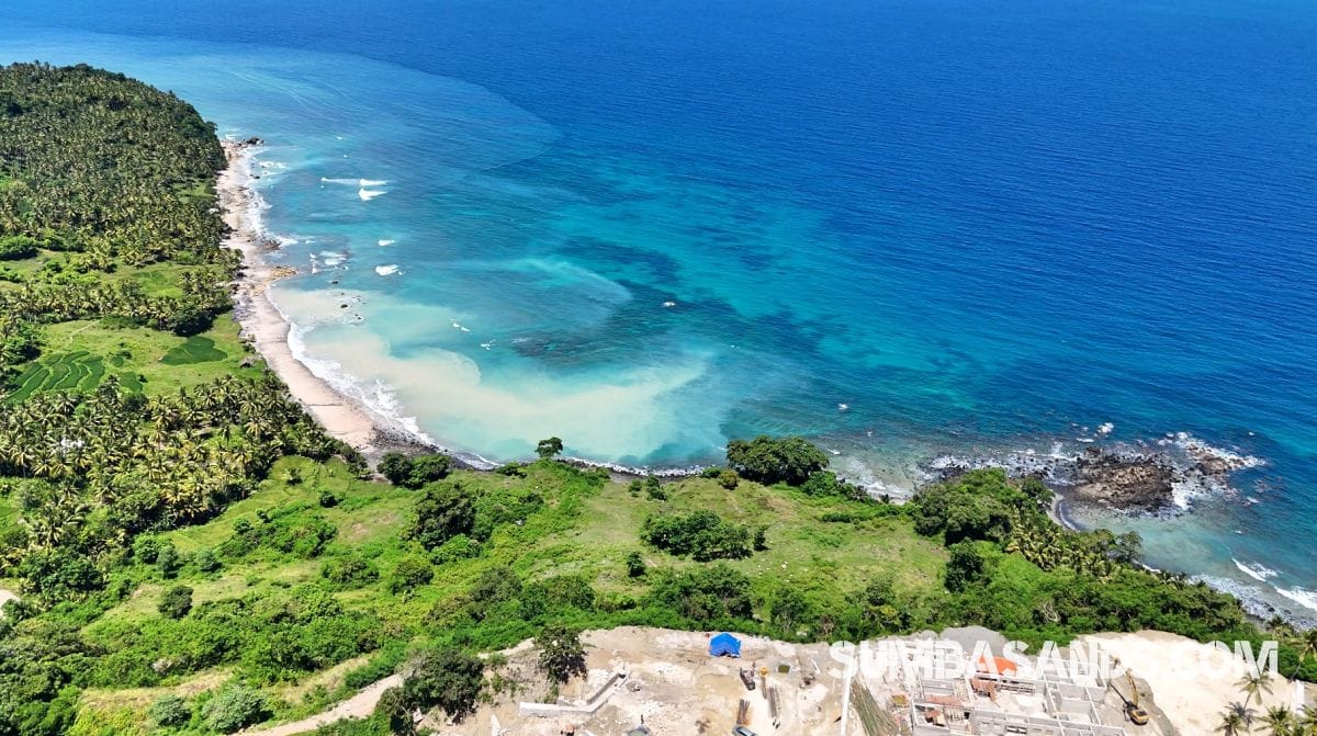 : A stunning drone shot of the 1.1-hectare Pahola Beachfront Cliff Estate, showing the lush green cliff edge meeting the turquoise waters of the Indian Ocean next to Rua Beach.